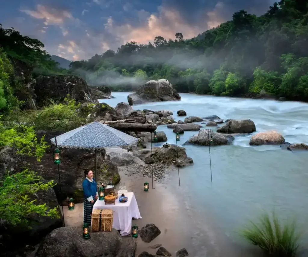 MUJER A LA ORILLA DEL RÍO CON MESA DE COMIDA Y BEBIDAS EN VALLE DE PUNAKHA, BUTAN