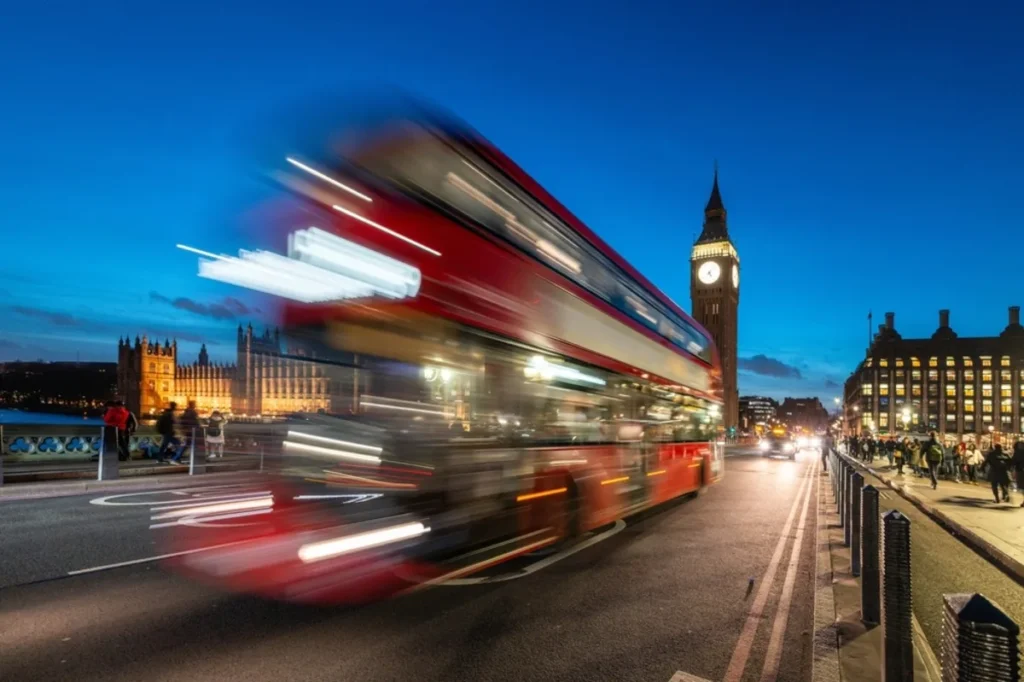 Autobús, Big Ben y personas caminando en Londres, ciudad de Reino Unido, que ahora exigirá ETA a viajeros mexicanos.